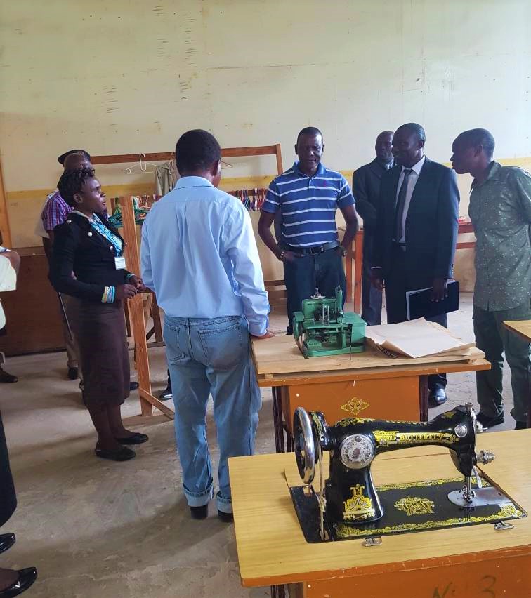 Picture of Francis Kasaila (in golf shirt) listens to a presentation from Fashion and Designing Instructor