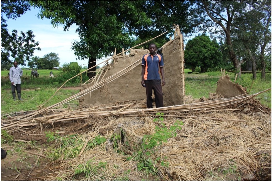 Picture of Figure 2: Boniface Kayange standing by his fallen house due to the flooding waters that passed through his house