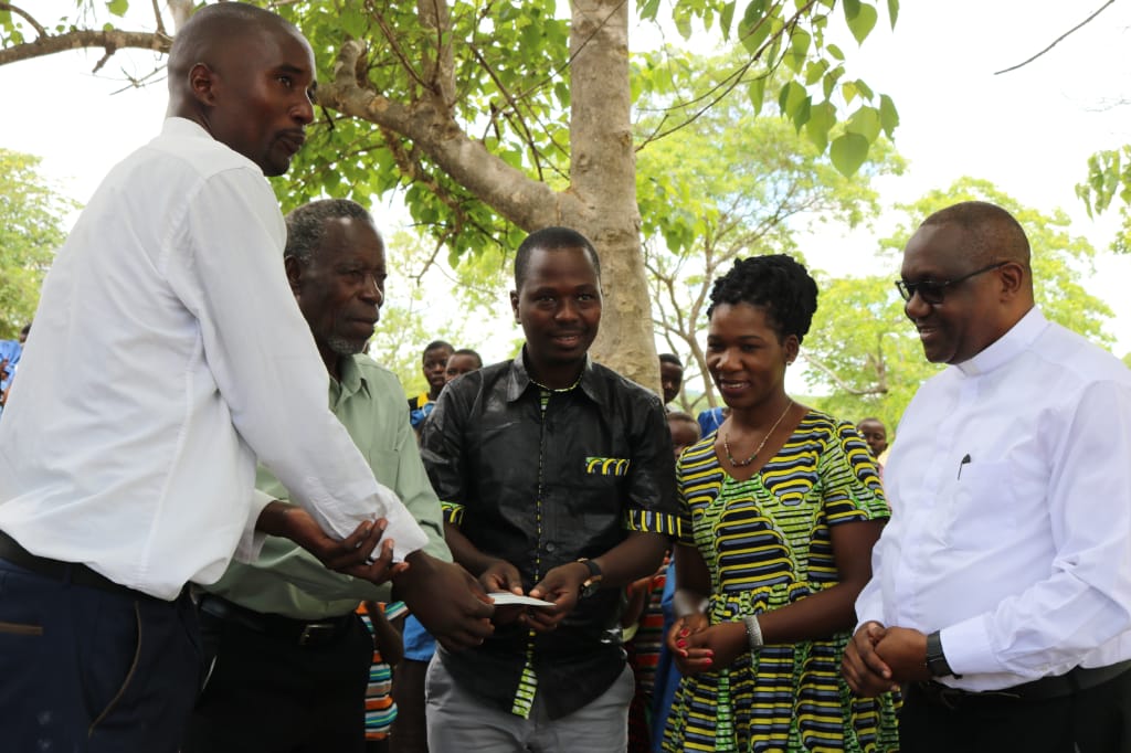 Charles Zimba handover the cheque to GVH Kyeghama and the Head teacher of Katili Primary School