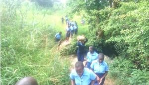 g9 Girls crossing a stream on their way to the surrounding villages