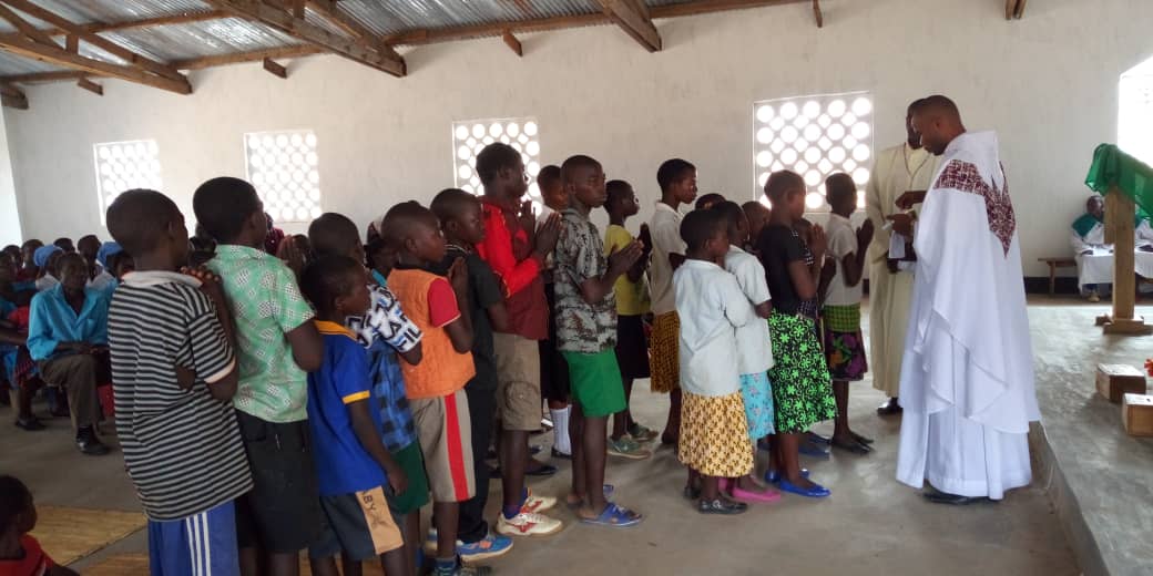 Father Mwafulirwa Administering First Communion to Junior Sunday School Children